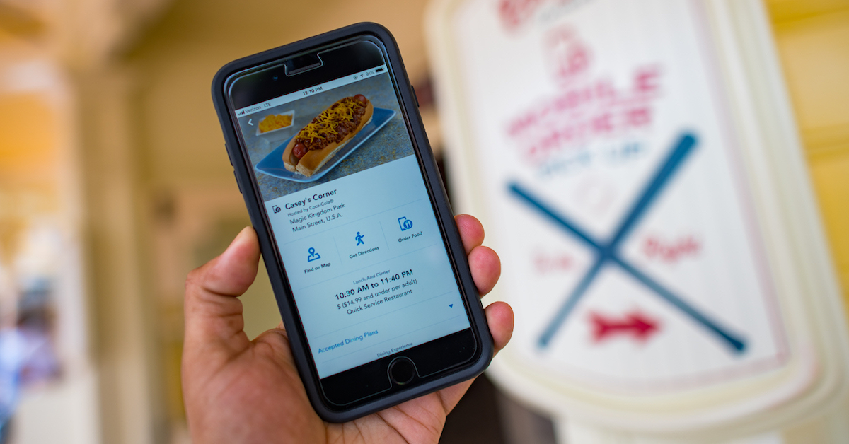 Mobile Order at Disney World and Disneyland restaurants, smartphone against a Mobile Order sign