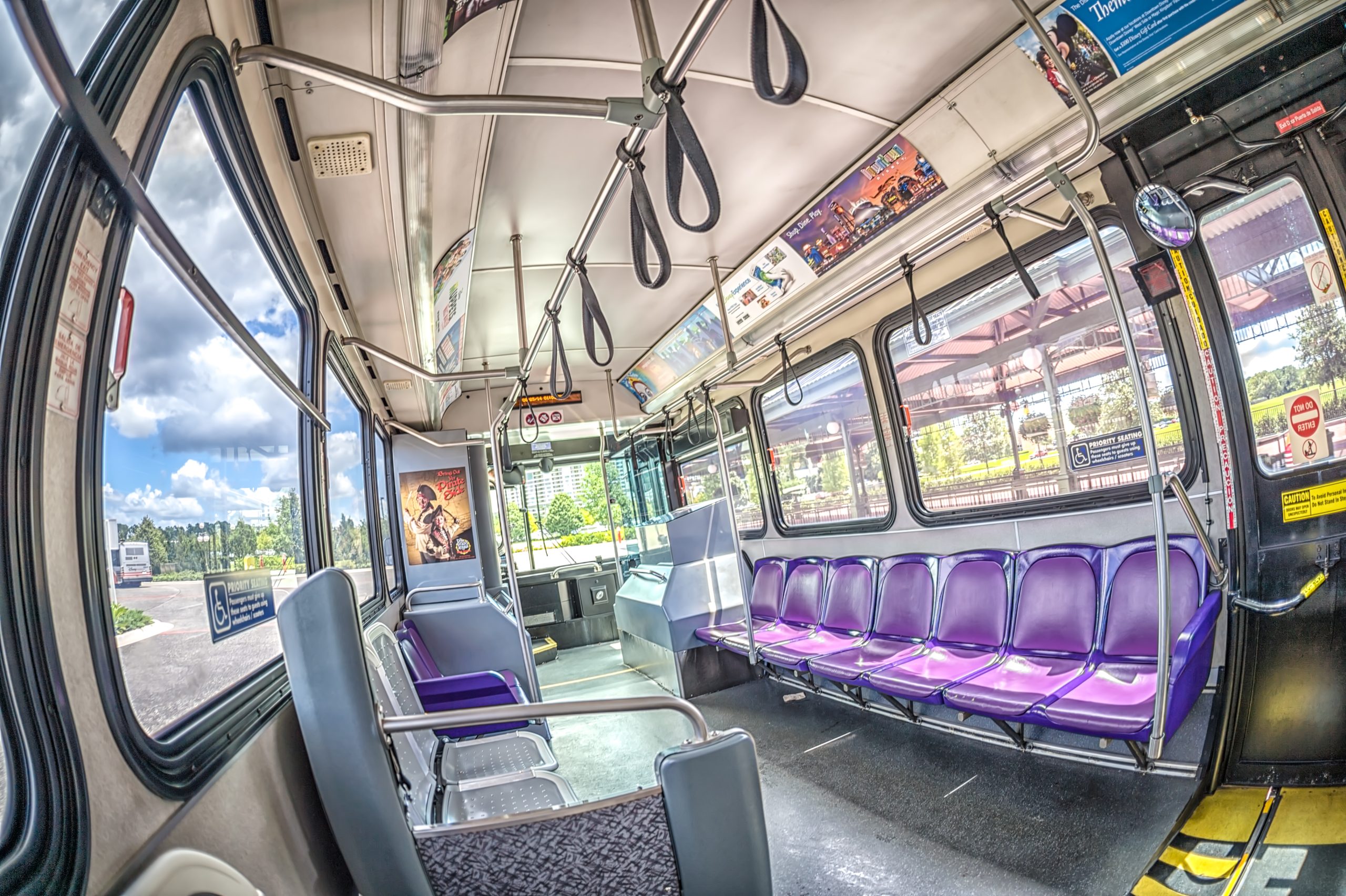 Interior of a Disney World bus, seats and hanging straps